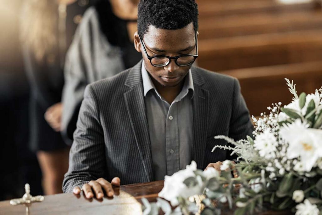 A person standing at a podium reading from notes while others listen with supportive expressions nearby.