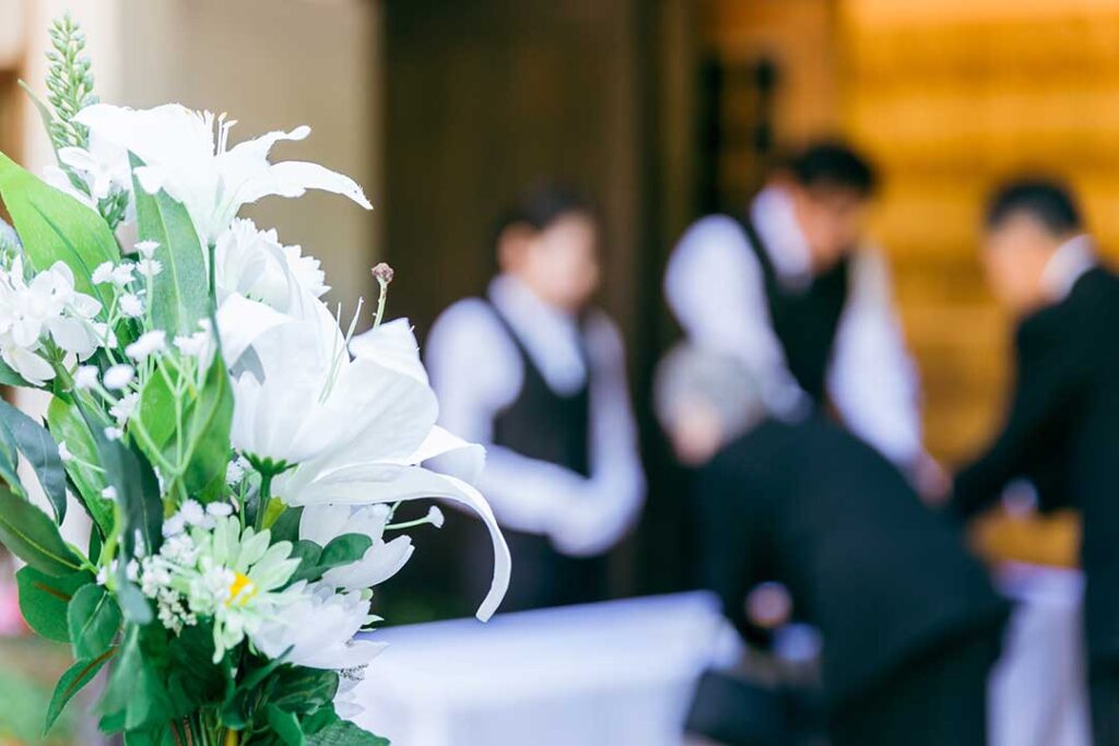 Family and friends share memories together outdoors, surrounded by framed photos, flowers, and personal keepsakes.