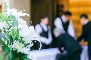 Family and friends share memories together outdoors, surrounded by framed photos, flowers, and personal keepsakes.