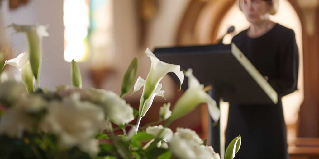 Family members gather quietly around flowers, photographs, and candles during a culturally diverse memorial ceremony.