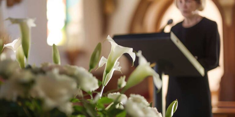 Family members gather quietly around flowers, photographs, and candles during a culturally diverse memorial ceremony.