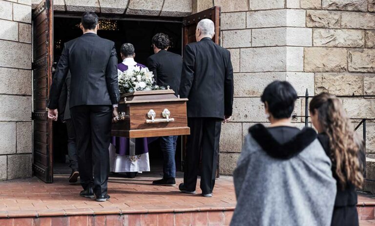 Family members review funeral documents and photographs at a dining table.